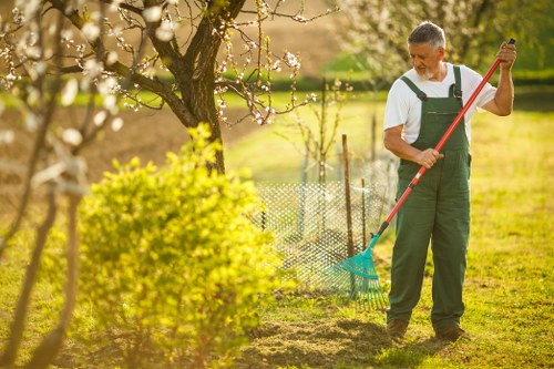 Gardener using hand tools wearing gloves and protective boots